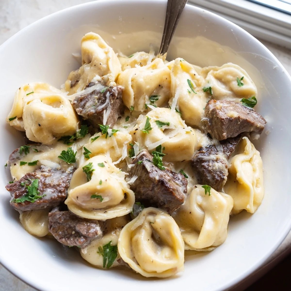 Garlic steak tortellini with seared sirloin pieces swimming in thick Parmesan cream sauce