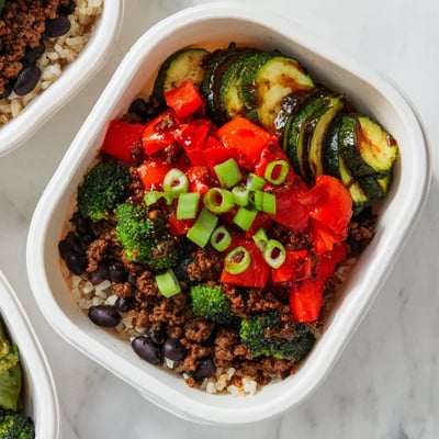 Top-down view of a meal prep container showing the Viral Hot Honey Ground Beef Bowl with avocado and green onions.